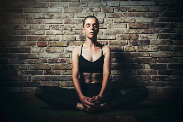 Jonge vrouw Blond in zwarte kleding praktijk yoga in donkere Studio Sport meditatie — Stockfoto