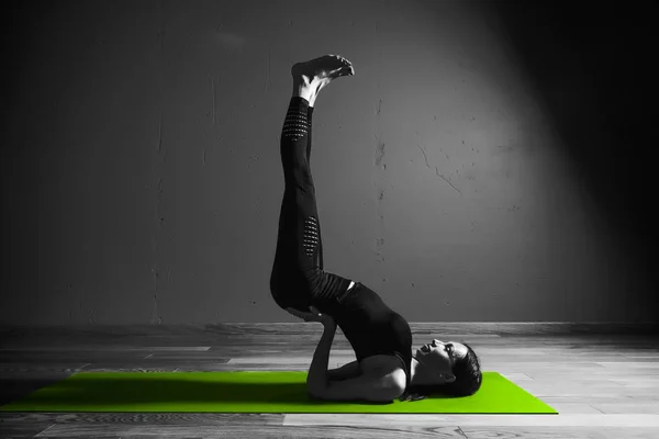 Black white photo of Young beautiful woman brunette in black clothes practice yoga in dark studio green mat Sport meditation monochrome — Stock Photo, Image