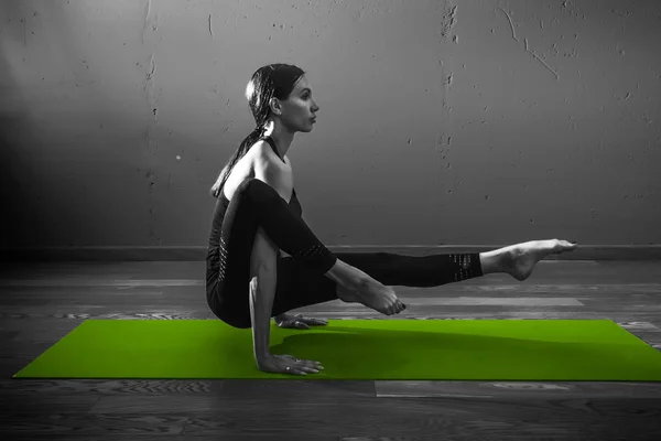 Black white photo of Young beautiful woman brunette in black clothes practice yoga in dark studio green mat Sport meditation monochrome — Stock Photo, Image
