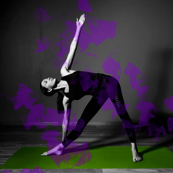 Black white photo of Young beautiful woman brunette in black clothes practice yoga utthita trikonasana in dark studio green mat Purple design element — Stock Photo, Image