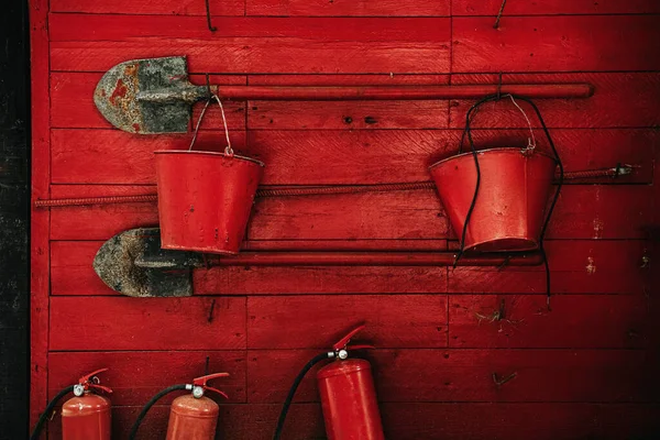 Fire extinguishing tools. Shovels, buckets, fire extinguishers on a red wall