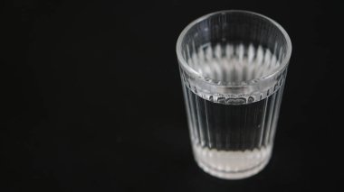 Siyah arka planda bir bardak su.