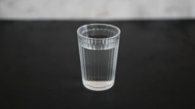 Siyah arka planda bir bardak su.