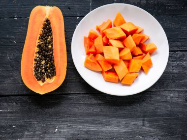 Olgun papaya soyulmuş ve beyaz bir tabakta dilimlenmiş.