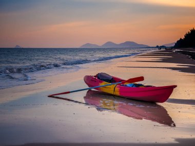 Beac üzerinde kayak tekne ile deniz üzerinde turuncu afernoon gökyüzü ile gün batımı