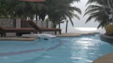 Sabahları donuk gökyüzünün altında Hindistan cevizi ağacı ve plaj manzaralı lüks tatil köylerinde ya da otellerde yüzme havuzu, Tayland