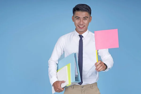 Asian young handsome student with book and blank flag, on light blue background — Stock Photo, Image