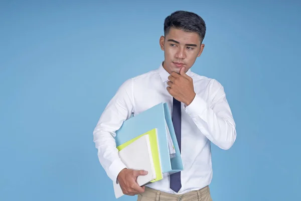 Asiatisk, ung, kjekk student med bok og tankegang, på lyseblå bakgrunn – stockfoto