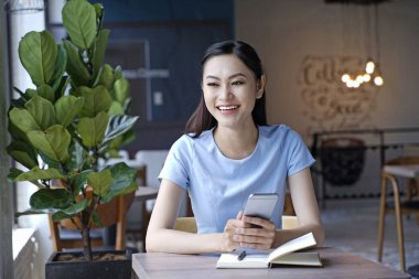 Asyalı oldukça çekici kadın akıllı kullanarak kahve dükkanında oturan