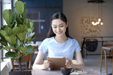 Asyalı oldukça çekici kadın akıllı kullanarak kahve dükkanında oturan