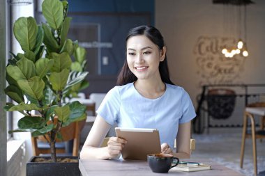 Asyalı oldukça çekici kadın akıllı kullanarak kahve dükkanında oturan