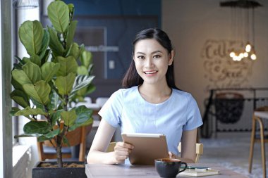 Asyalı oldukça çekici kadın akıllı kullanarak kahve dükkanında oturan