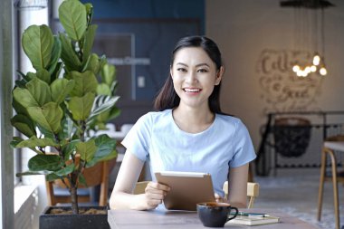 Asyalı oldukça çekici kadın akıllı kullanarak kahve dükkanında oturan