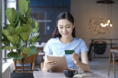 Asyalı oldukça çekici kadın akıllı kullanarak kahve dükkanında oturan