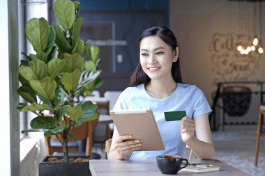 Asyalı oldukça çekici kadın akıllı kullanarak kahve dükkanında oturan