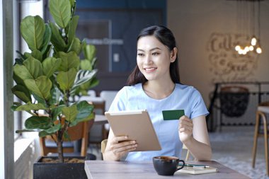 Asyalı oldukça çekici kadın akıllı kullanarak kahve dükkanında oturan