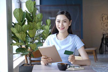 Asyalı oldukça çekici kadın akıllı kullanarak kahve dükkanında oturan