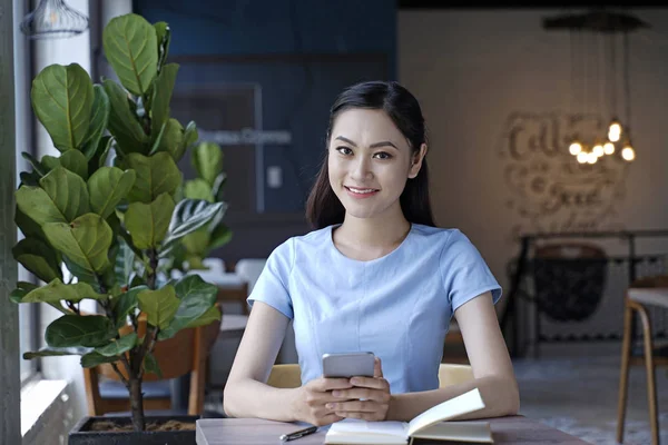 Asyalı oldukça çekici kadın akıllı kullanarak kahve dükkanında oturan