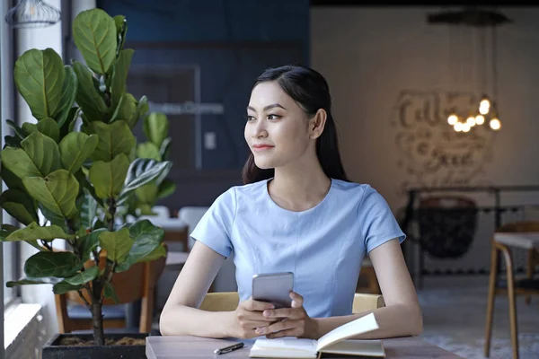 Asyalı oldukça çekici kadın akıllı kullanarak kahve dükkanında oturan