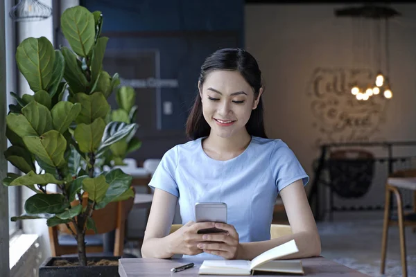 Asyalı oldukça çekici kadın akıllı kullanarak kahve dükkanında oturan