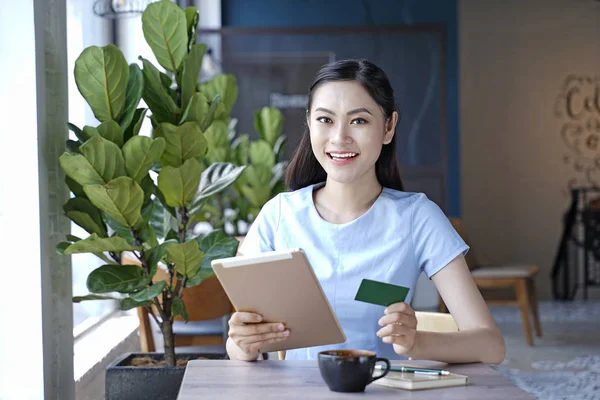 Asyalı oldukça çekici kadın akıllı kullanarak kahve dükkanında oturan