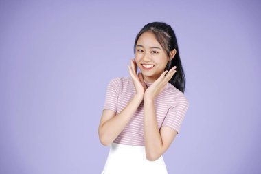 Pembe gömlek el hareketi ile Asyalı genç genç güzel neşeli kız, mor arka plan üzerinde