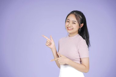 Pembe gömlek el hareketi ile Asyalı genç genç güzel neşeli kız, mor arka plan üzerinde