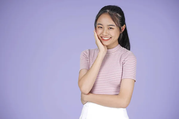 Mladé děvče z Asie, krásná veselá dívka s ručním gestem v růžové košili, na fialovém pozadí — Stock fotografie