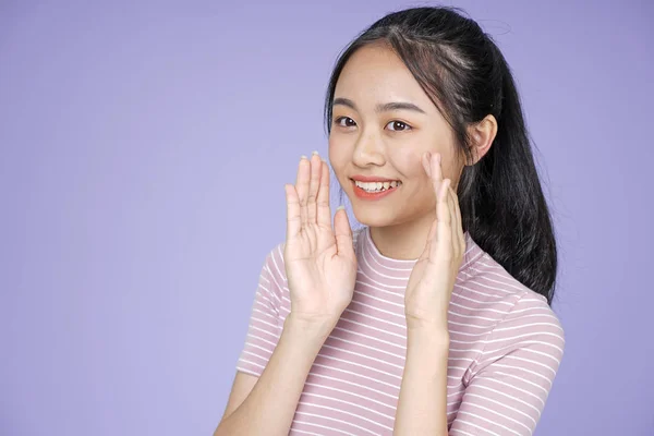 Aziatische jonge tiener mooie vrolijke meid met hand gebaar Whisper in roze shirt, op Violet achtergrond — Stockfoto