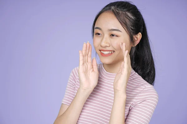 Aziatische jonge tiener mooie vrolijke meid met hand gebaar Whisper in roze shirt, op Violet achtergrond — Stockfoto