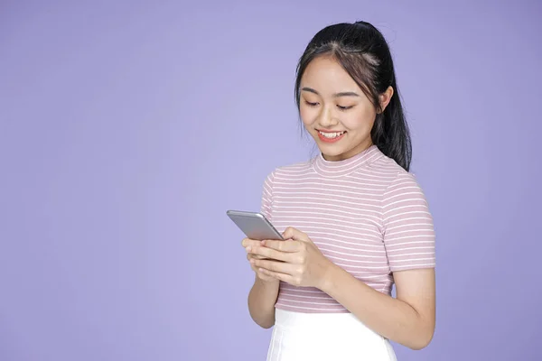 Asian młody Nastoletni piękny wesoły dziewczyna z inteligentny telefon w różowy koszula, na fioletowy tło — Zdjęcie stockowe