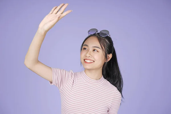 Aziatische jonge tiener mooie vrolijke meid Vermijd zonlicht met de hand in roze shirt, op Violet achtergrond — Stockfoto