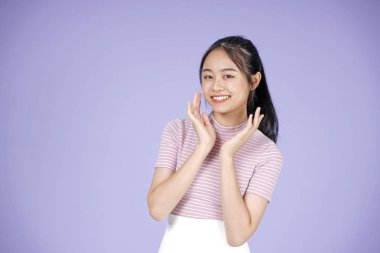 Pembe gömlek el hareketi ile Asyalı genç genç güzel neşeli kız, mor arka plan üzerinde