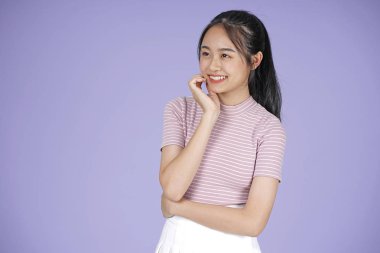 Pembe gömlek el hareketi ile Asyalı genç genç güzel neşeli kız, mor arka plan üzerinde