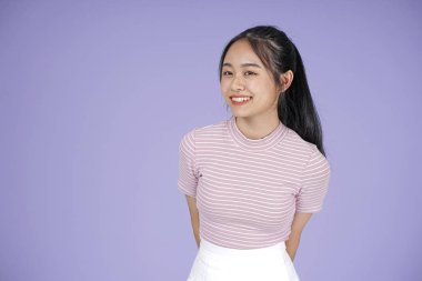 Pembe gömlek el hareketi ile Asyalı genç genç güzel neşeli kız, mor arka plan üzerinde