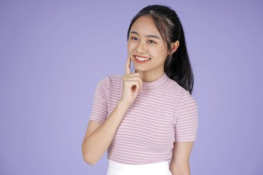 Pembe gömlek el hareketi ile Asyalı genç genç güzel neşeli kız, mor arka plan üzerinde