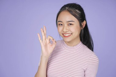 Pembe gömlek el hareketi ile Asyalı genç genç güzel neşeli kız, mor arka plan üzerinde