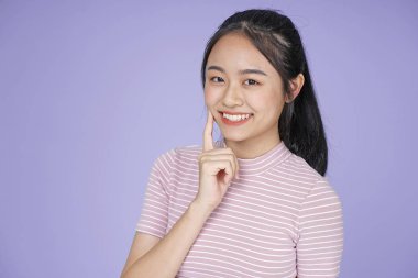 Pembe gömlek el hareketi ile Asyalı genç genç güzel neşeli kız, mor arka plan üzerinde