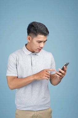 Mavi arka plan akıllı telefon ile Asyalı genç yakışıklı çekici adam