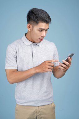 Mavi arka plan akıllı telefon ile Asyalı genç yakışıklı çekici adam