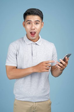 Mavi arka plan akıllı telefon ile Asyalı genç yakışıklı çekici adam