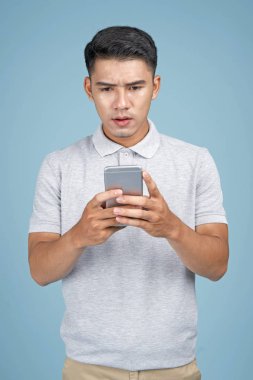 Mavi arka plan akıllı telefon ile Asyalı genç yakışıklı çekici adam