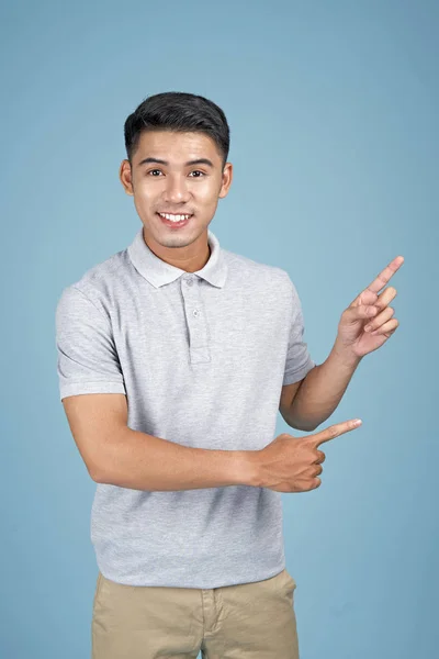 Aziatische jonge knappe aantrekkelijke man met gezichtsuitdrukking en hand tonen bericht op blauwe achtergrond — Stockfoto