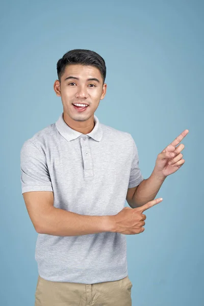 Asiatique jeune bel homme attrayant avec l'expression du visage et la main montrant le message sur fond bleu — Photo