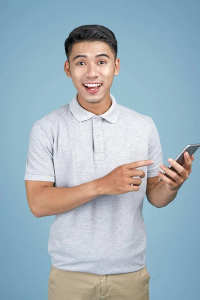 Asiatico giovane bello attraente uomo con smart phone su sfondo blu — Foto Stock