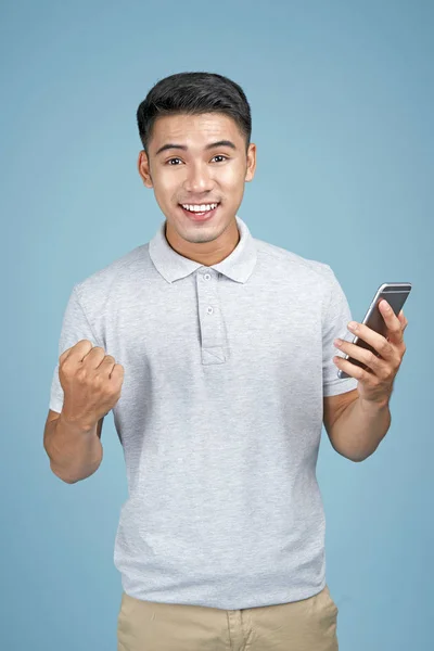 Asiático jovem bonito atraente homem com telefone inteligente no fundo azul — Fotografia de Stock