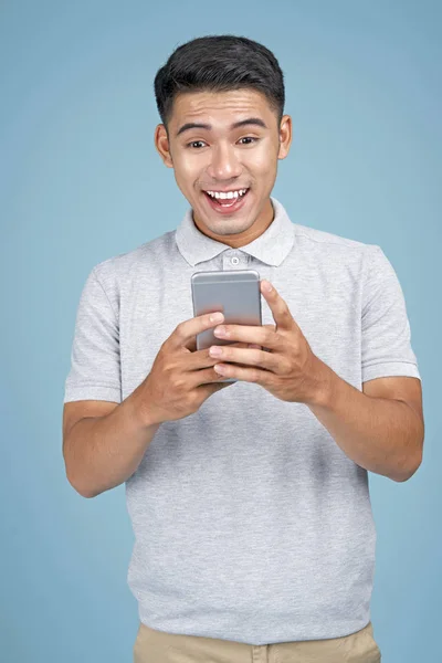 Азіатський молодий красивий привабливий чоловік з смарт-телефон на синьому фоні — стокове фото