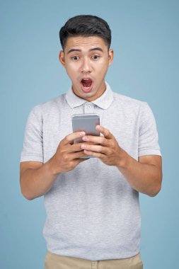 Mavi arka plan akıllı telefon ile Asyalı genç yakışıklı çekici adam