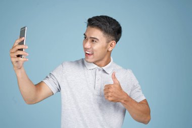 Mavi arka plan akıllı telefon ile Asyalı genç yakışıklı çekici adam