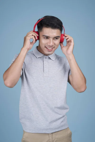 Азіатський молодий красивий привабливий чоловік слухає музику з виразом обличчя на синьому фоні — стокове фото
